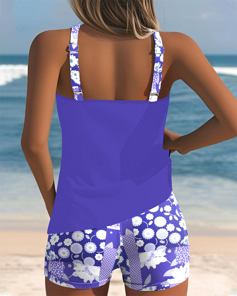 Tankini morada sin mangas con short de baño estampado floral blanco, vista trasera.