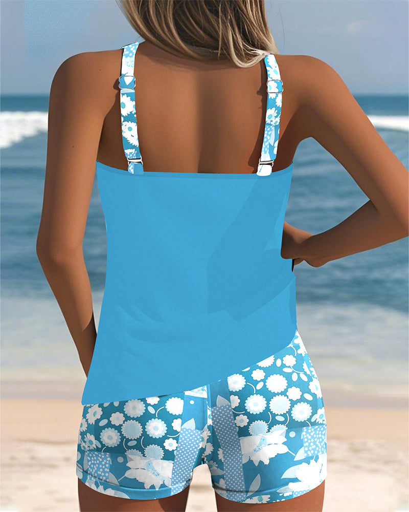 Tankini azul celeste sin mangas con short de baño estampado floral blanco, vista trasera.