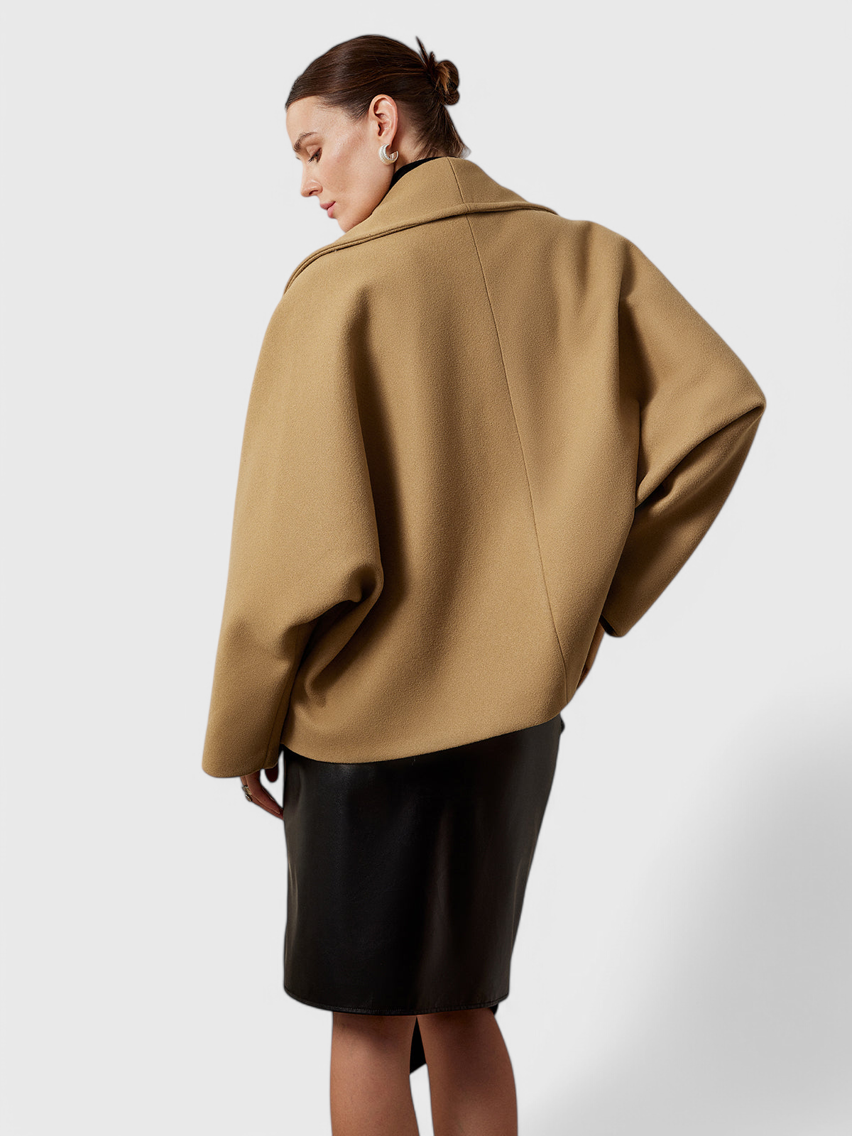 Abrigo de tweed beige visto por detrás, con corte amplio y manga suelta