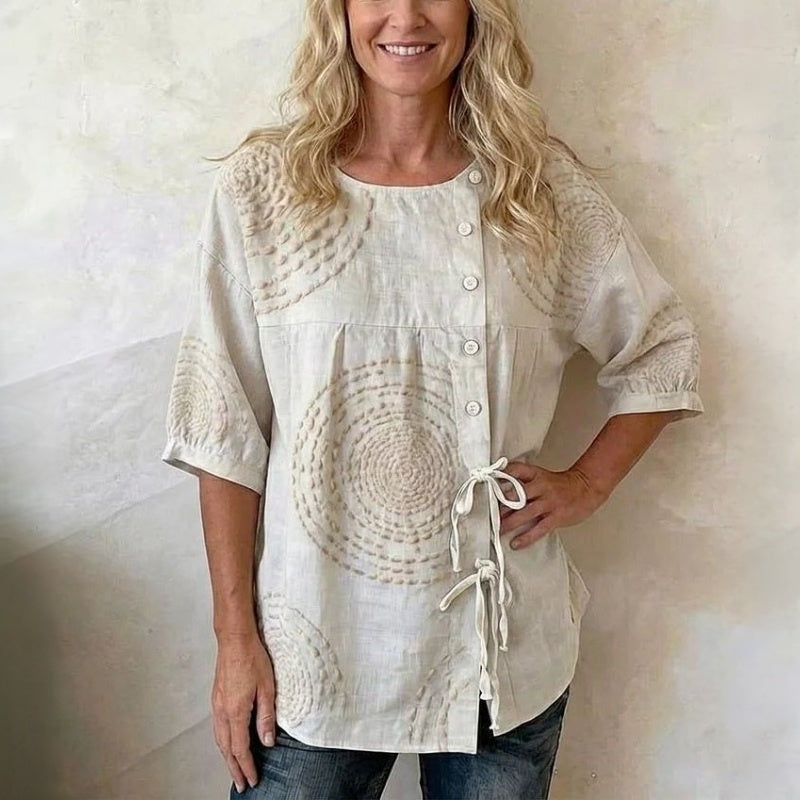 Blusa beige con botones y estampado circular artesanal; cordones ajustables en el lateral