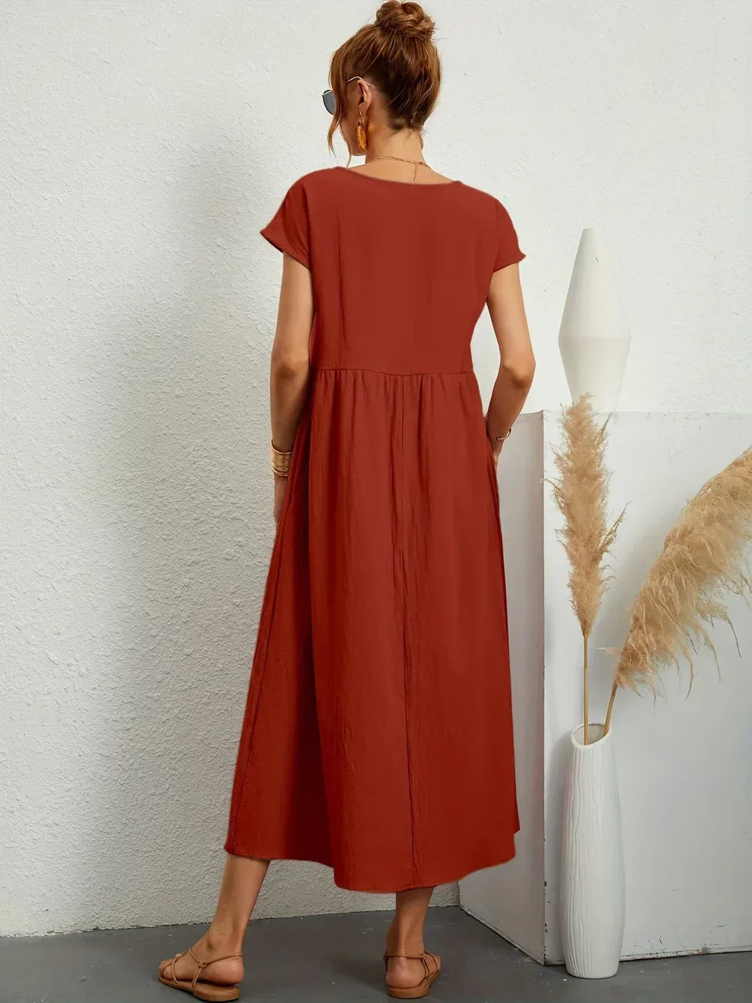 Vestido midi fluido marrón óxido visto por la espalda, mangas cortas y cintura fruncida