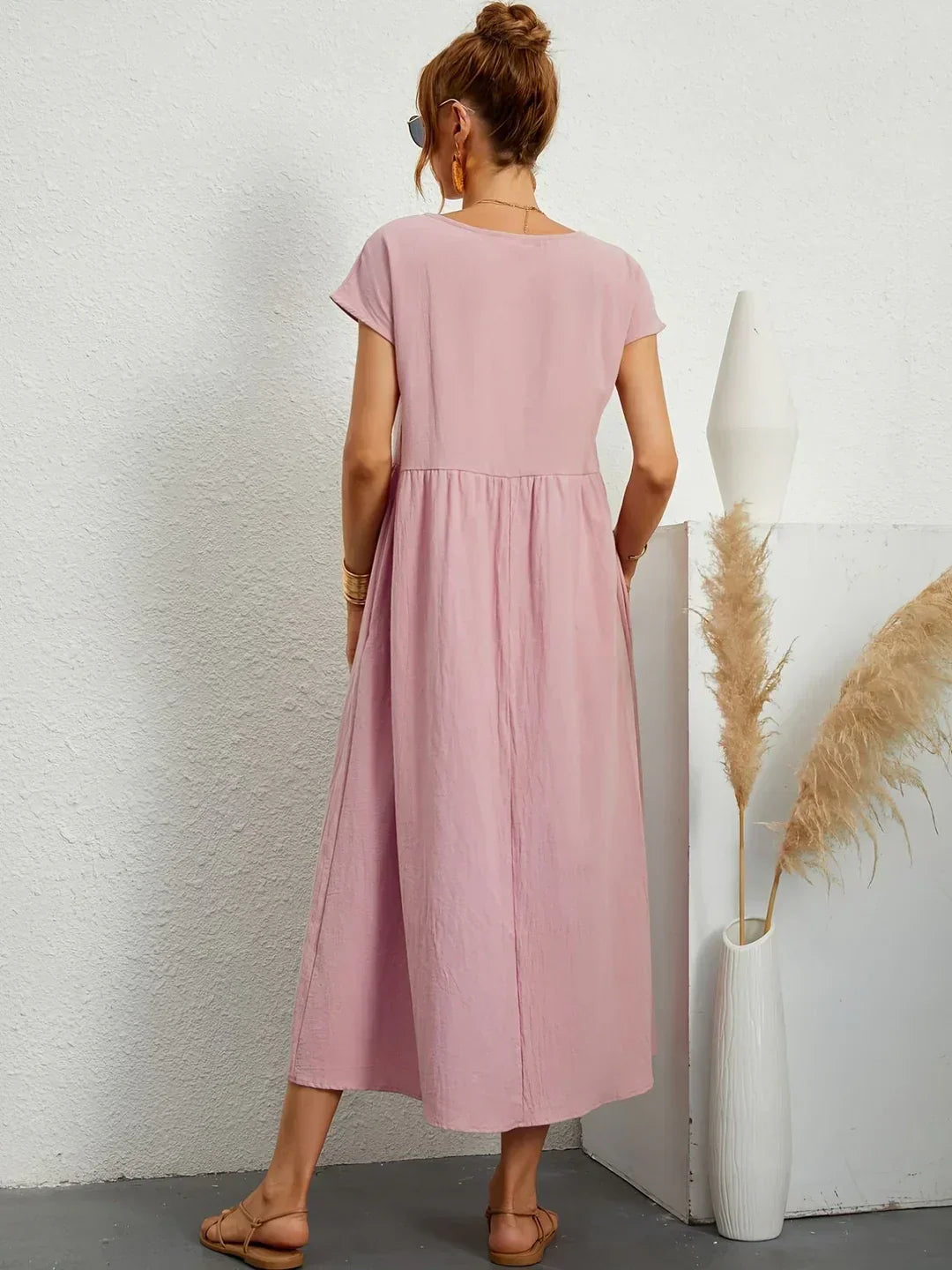 Vestido midi fluido rosa visto por la espalda, mangas cortas y cintura fruncida