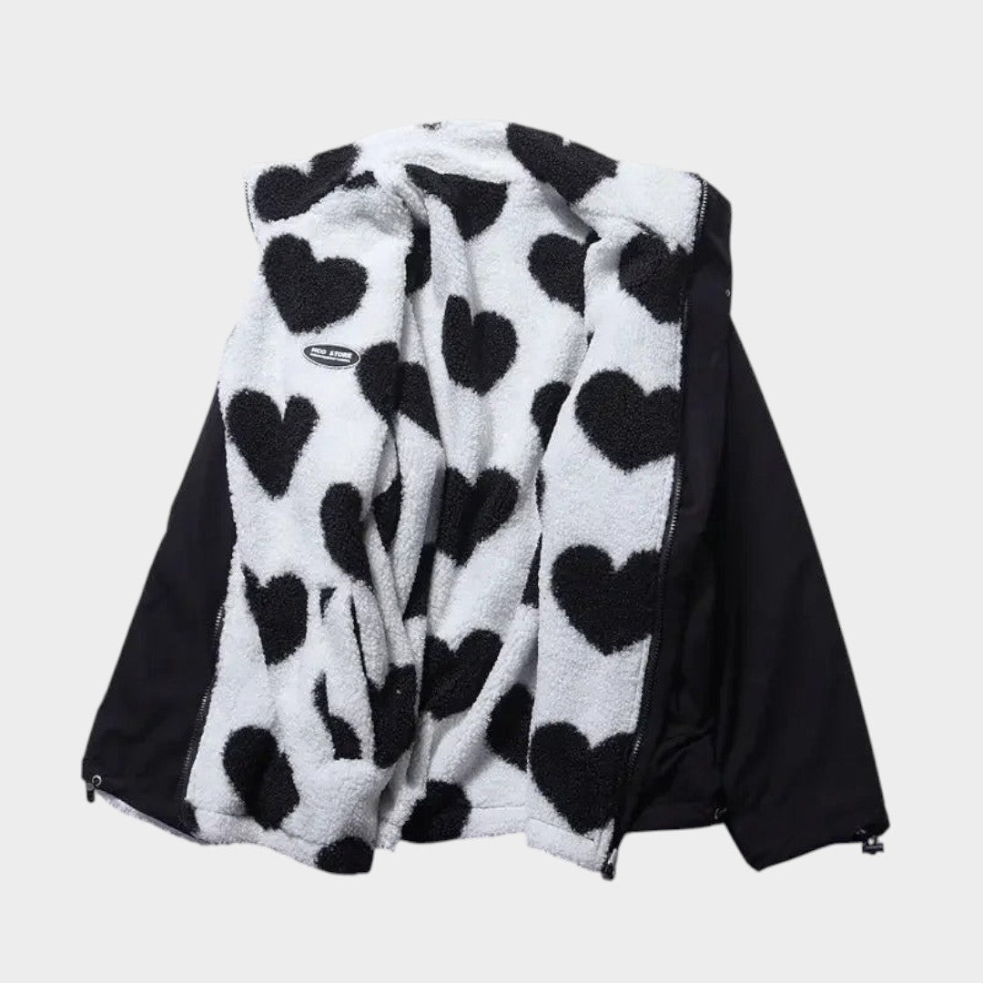 Chaqueta reversible con polar claro de corazones negros y panel exterior oscuro.