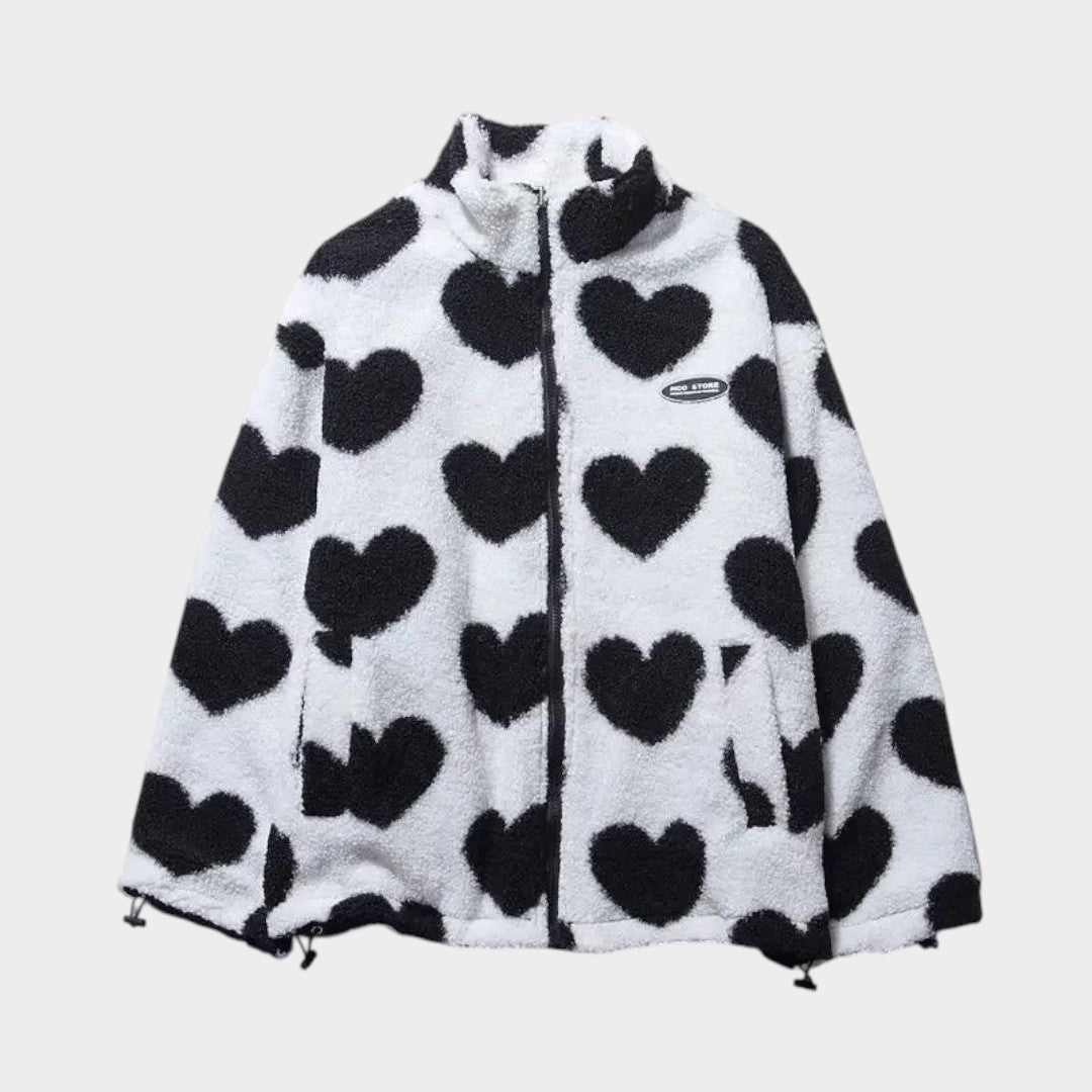 Chaqueta reversible de forro polar claro con corazones negros, capucha y cierre.