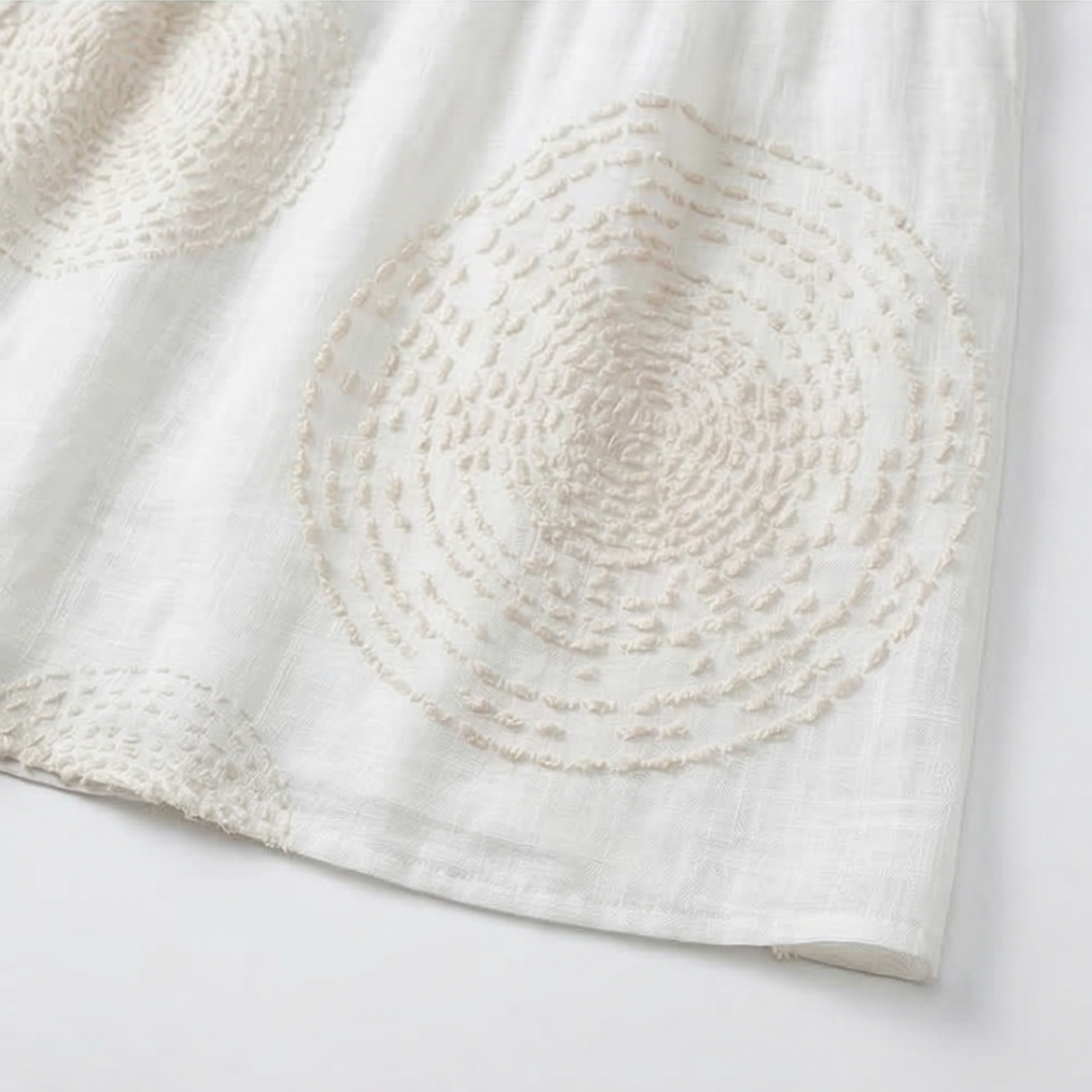Vestido blanco de mujer con bordado circular en la falda y caída suelta