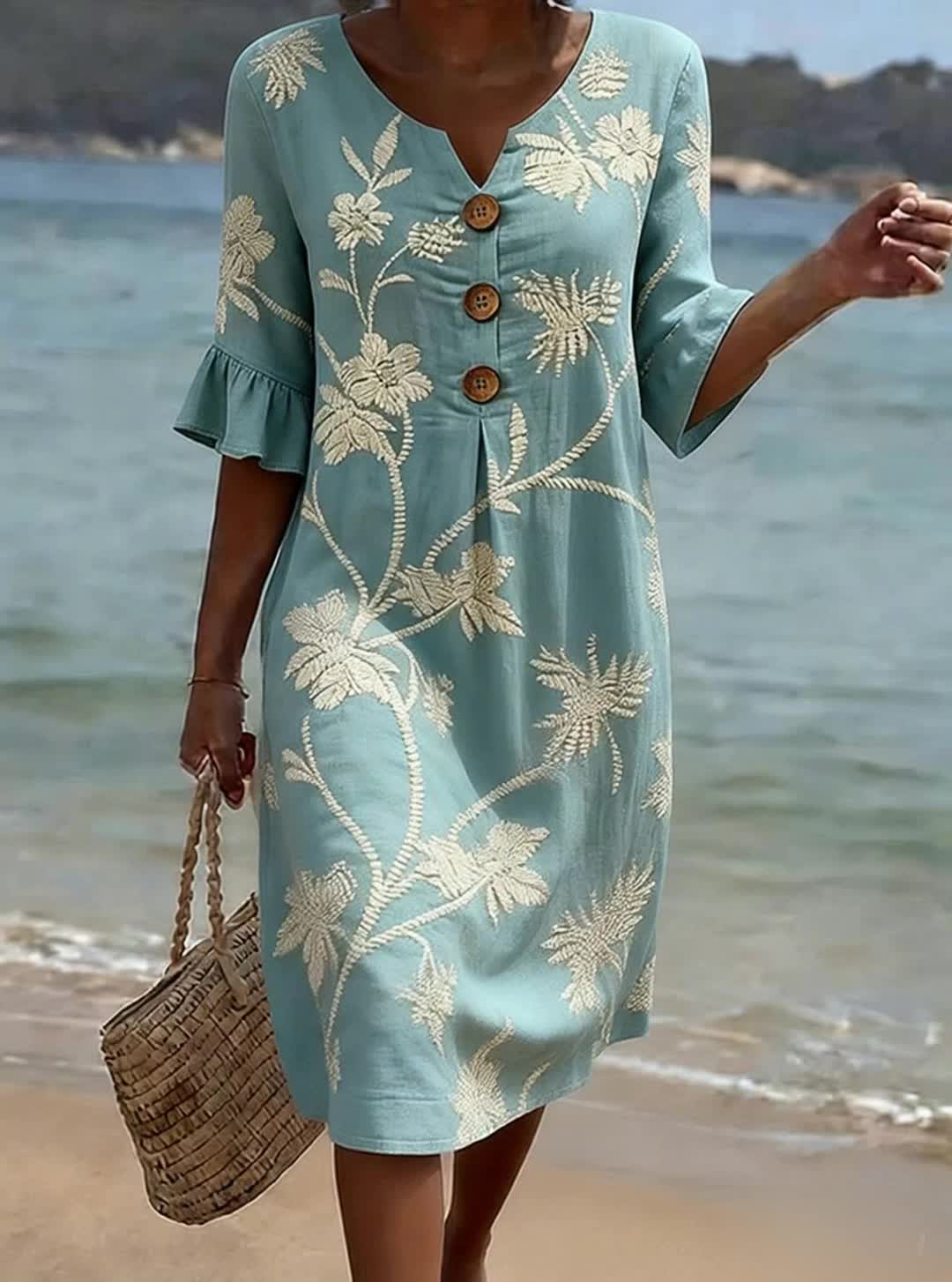 Vestido azul con estampado floral, cuello redondo y mangas acampanadas con botones