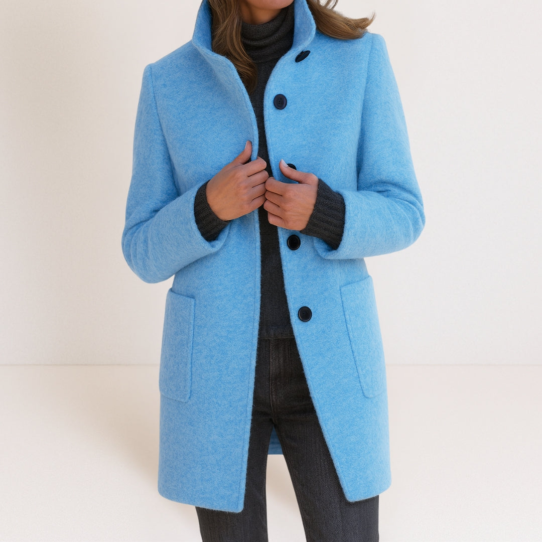 Chaqueta de mujer azul claro con cuello alto, botones frontales y bolsillos tipo parche.
