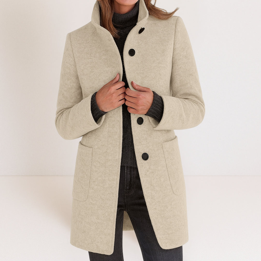 Chaqueta de mujer beige claro con cuello alto, botones frontales y bolsillos tipo parche.