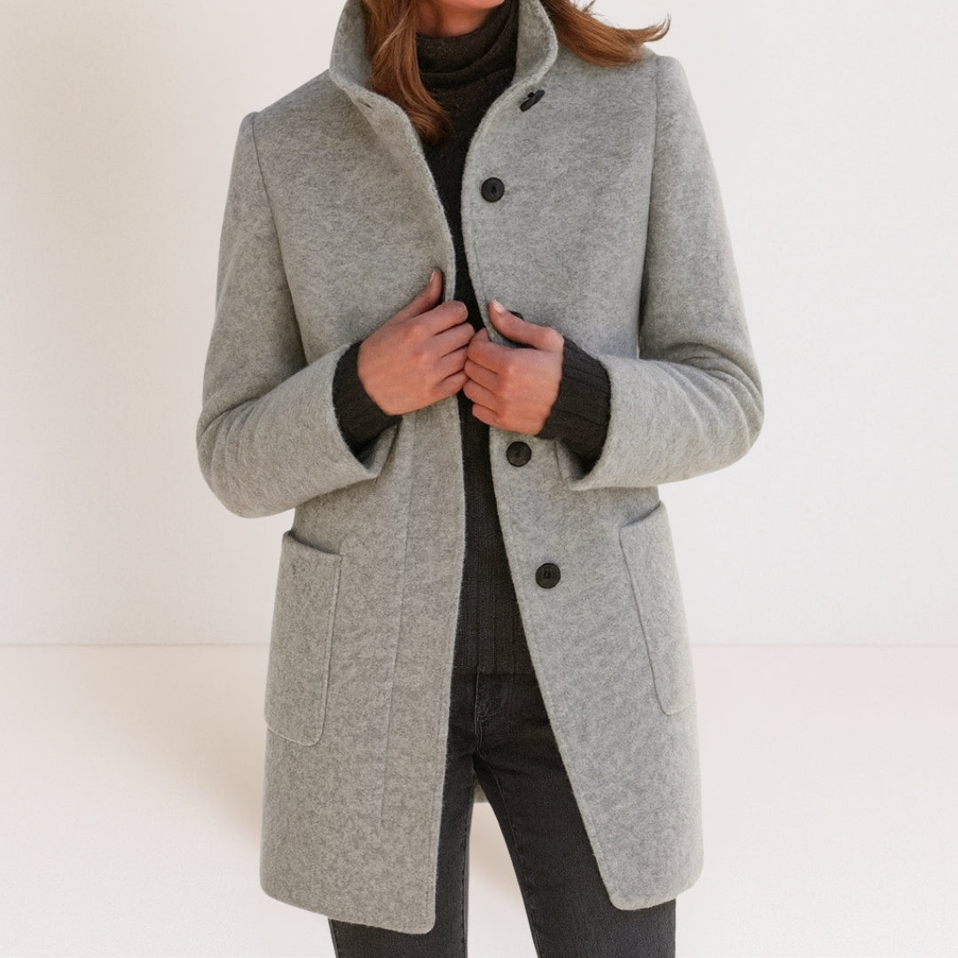 Chaqueta de mujer gris claro con cuello alto, botones frontales y bolsillos tipo parche.