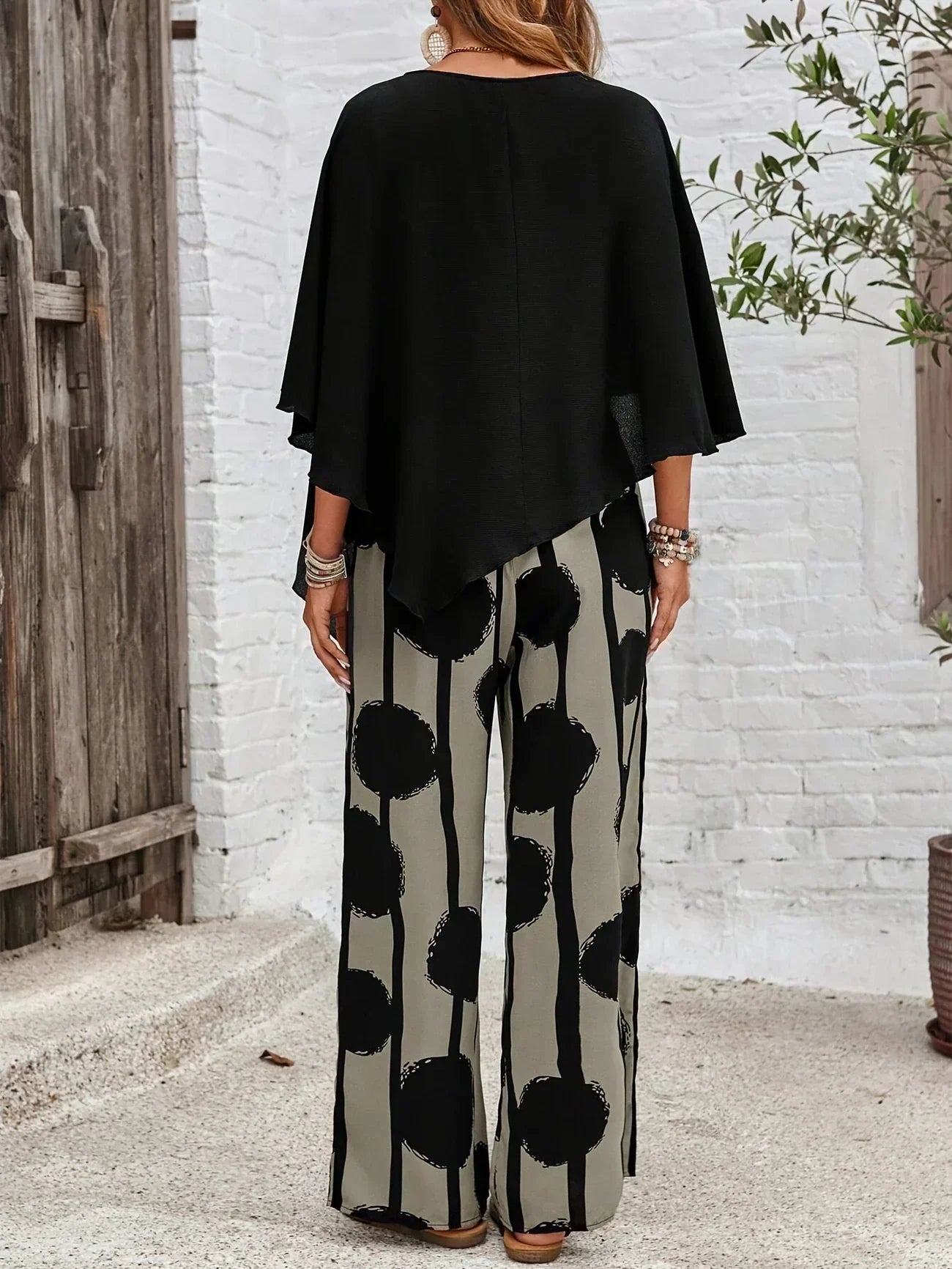 Conjunto boho negro visto por la espalda: top asimétrico y pantalón ancho de círculos