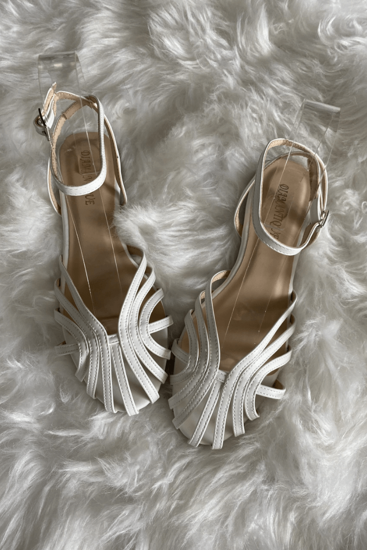 Sandalias de tacón blancas con tiras decorativas y detalle joya en la parte frontal