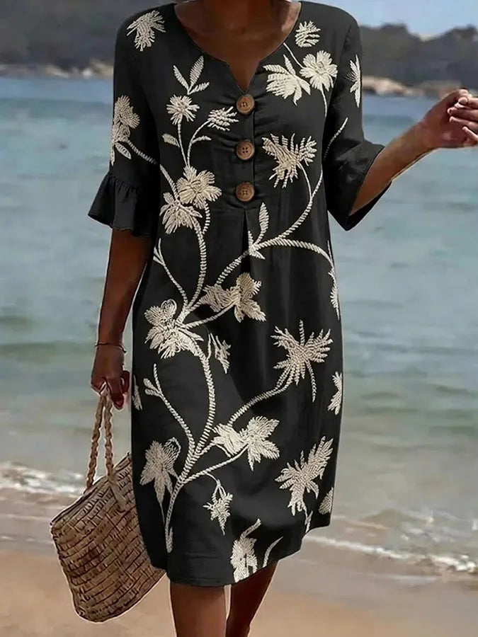 Vestido informal negro con estampado floral blanco, cuello V y botones al frente