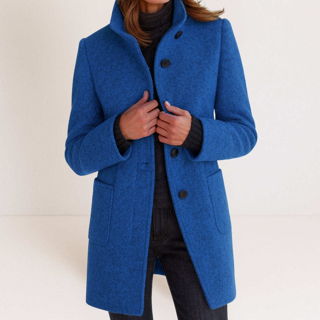 Chaqueta de mujer azul con cuello alto, botones frontales y bolsillos tipo parche.