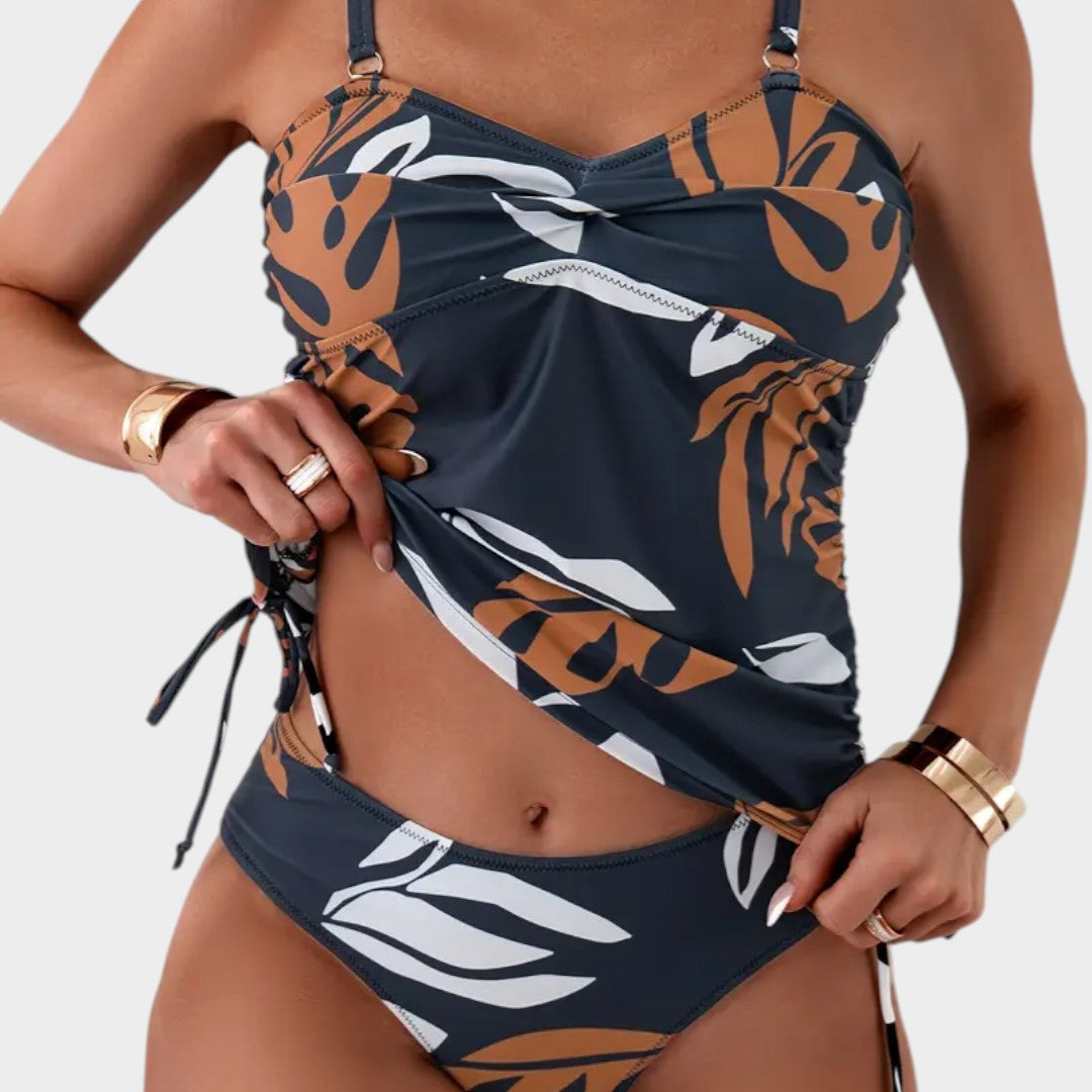 Bañador entero azul marino con estampado tropical naranja y blanco, fruncido y cordones.