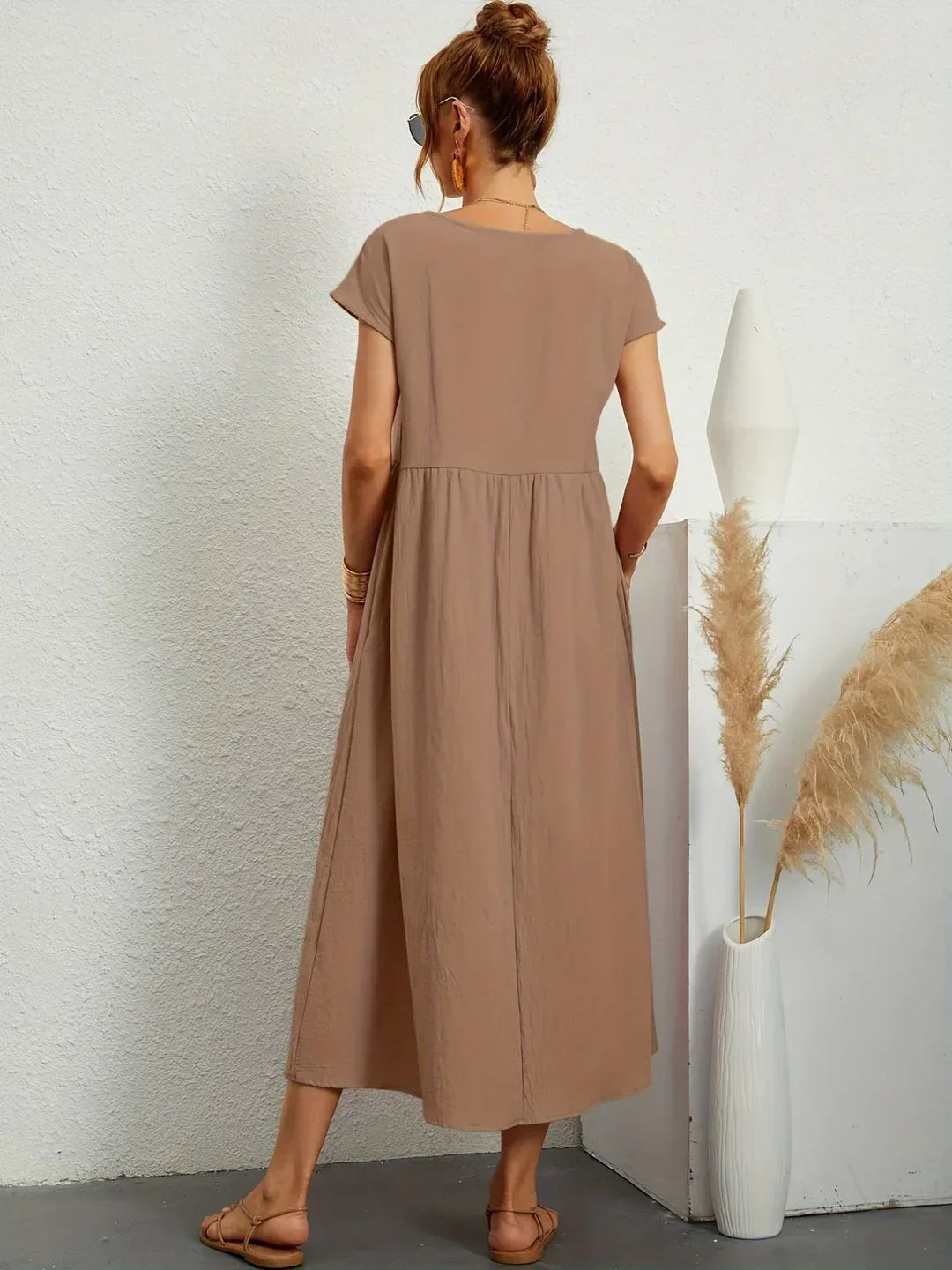 Vestido midi fluido color taupe visto por la espalda, mangas cortas y cintura fruncida
