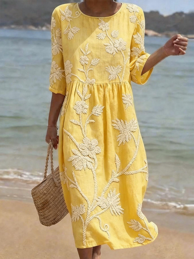 Vestido informal amarillo con cuello redondo, estampado floral bordado y cintura fruncida.