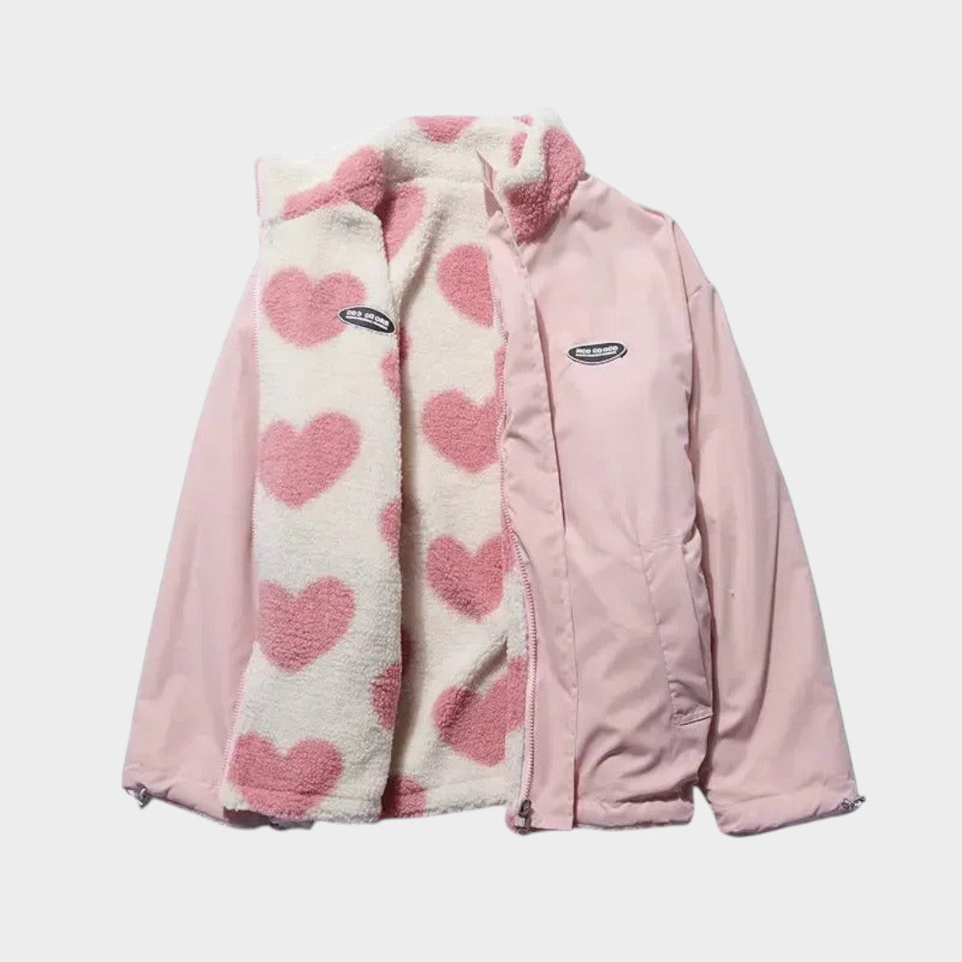Chaqueta reversible con forro polar claro de corazones rosas y panel exterior rosa.