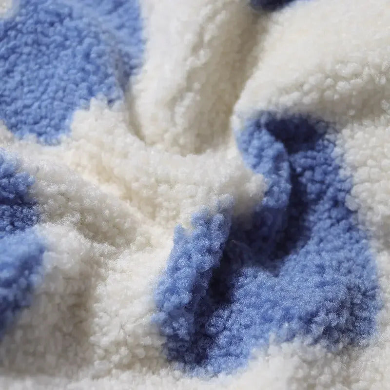 Chaqueta de borrego con corazones azules y textura esponjosa sobre fondo crema