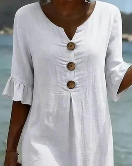Vestido blanco con escote en V y botones de madera en el centro; mangas con volante