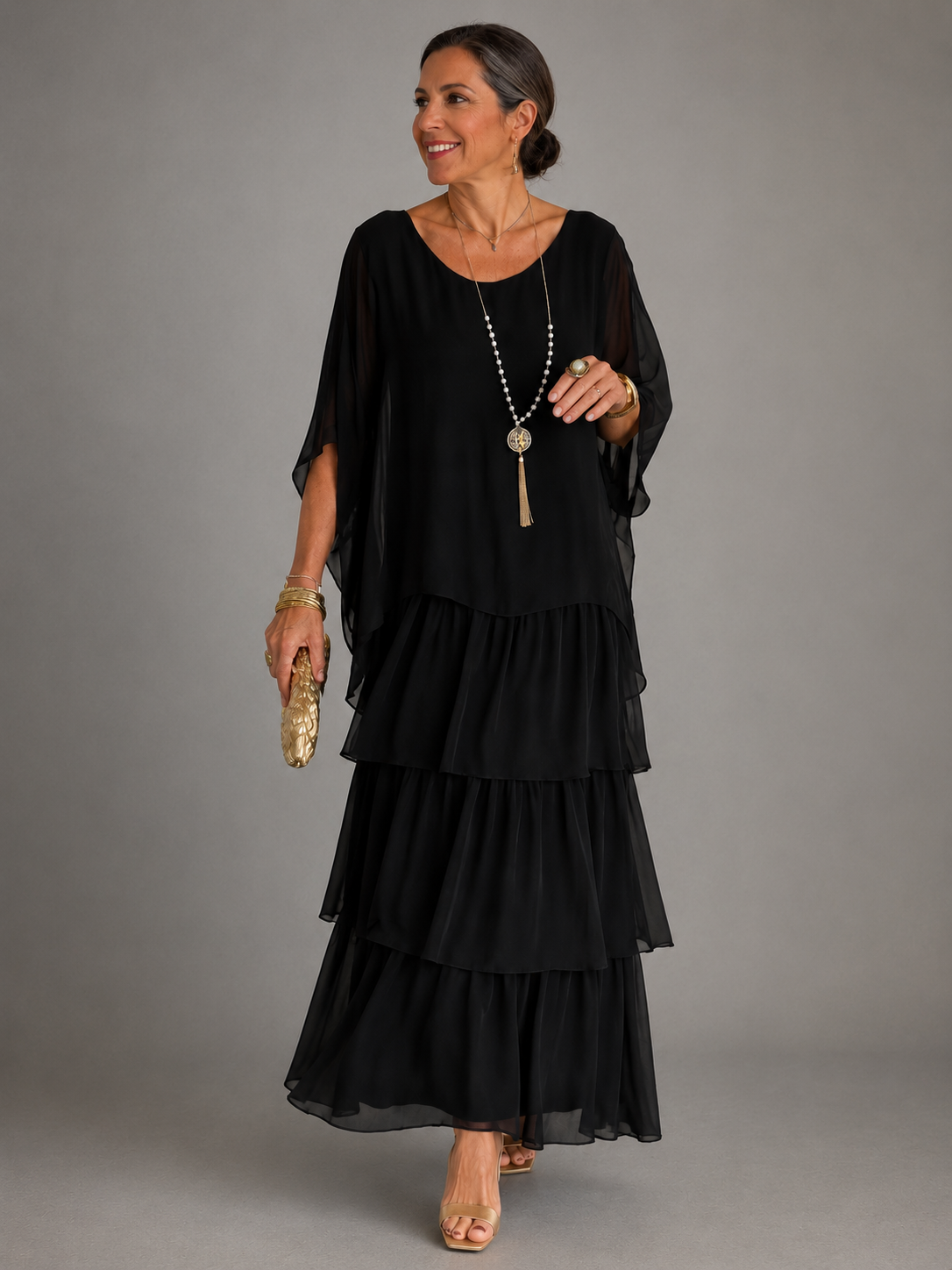 Vestido largo negro fluido con volantes escalonados y manga tipo capa, de gasa